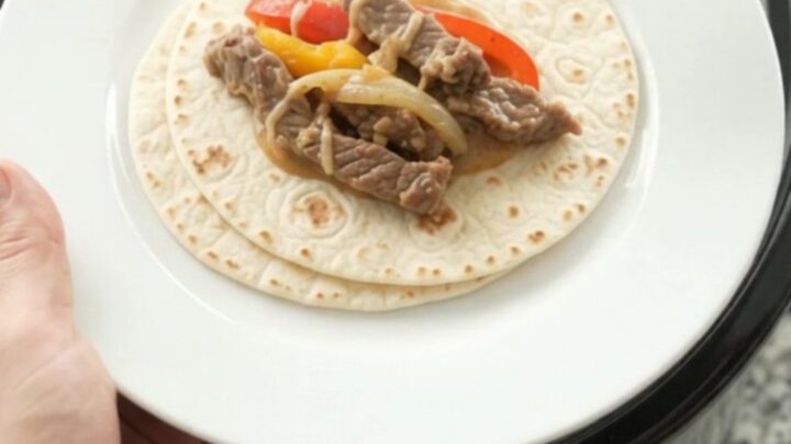 Slow cooker fajita skirt steak with peppers and creamy cheese sauce in a black crock