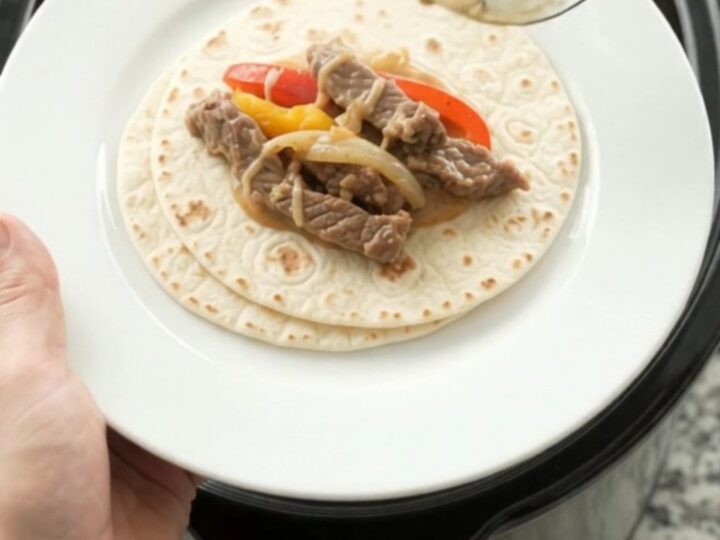 Slow cooker fajita skirt steak with peppers and creamy cheese sauce in a black crock