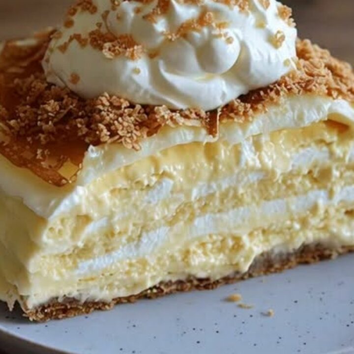 A close-up of a slice of layered crepe cake with creamy filling on a speckled plate.