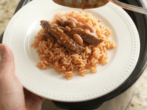 Slow cooker filled with cheesy enchilada skirt steak and beans