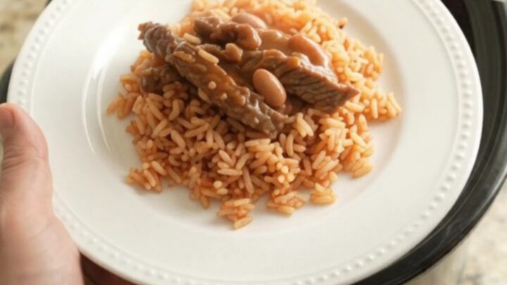 Slow cooker filled with cheesy enchilada skirt steak and beans