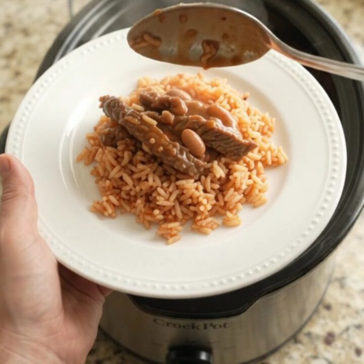 Slow cooker filled with cheesy enchilada skirt steak and beans