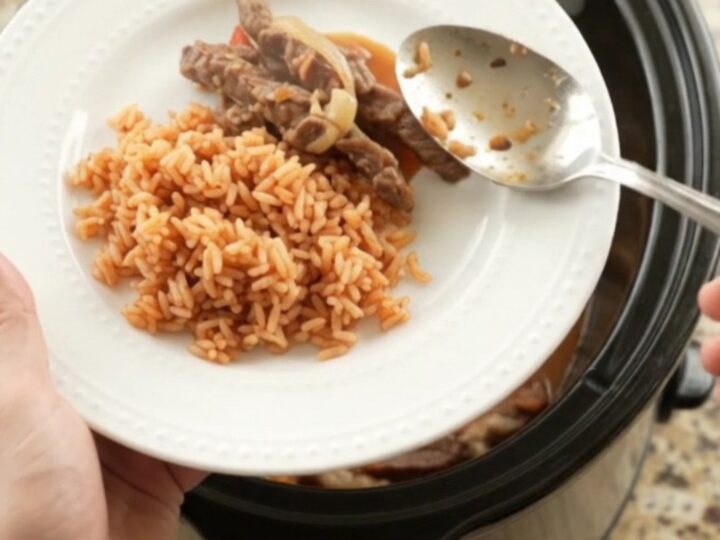 Slow cooker filled with cheesy fajita steak and peppers, steam rising.
