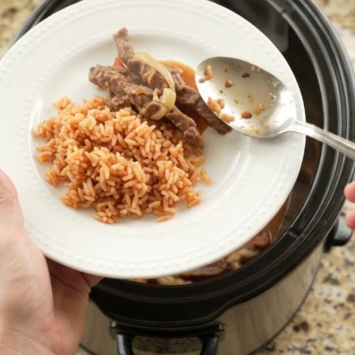 Slow cooker filled with cheesy fajita steak and peppers, steam rising.