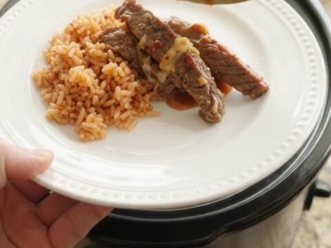 Slow cooker filled with tender skirt steak strips in a chipotle pineapple sauce, topped with melted Oaxaca cheese.