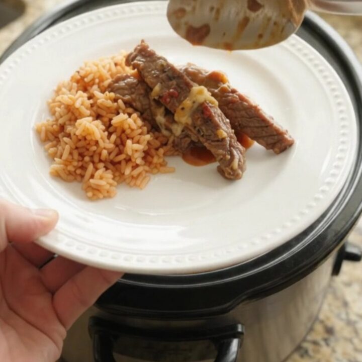 Slow cooker filled with tender skirt steak strips in a chipotle pineapple sauce, topped with melted Oaxaca cheese.