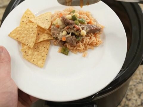 Slow-cooker pepper jack poblano skirt steak with hominy, bubbling in a black Crockpot