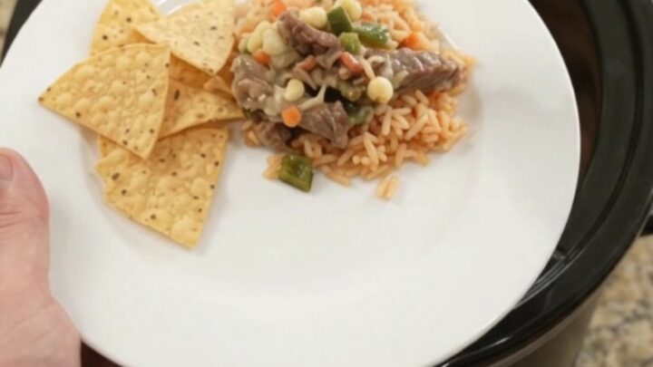 Slow-cooker pepper jack poblano skirt steak with hominy, bubbling in a black Crockpot