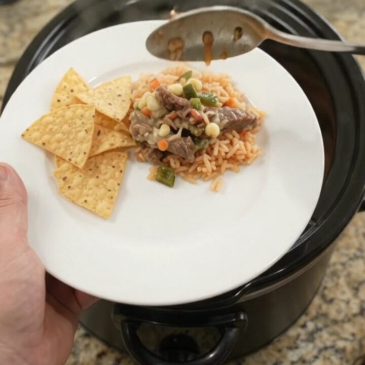 Slow-cooker pepper jack poblano skirt steak with hominy, bubbling in a black Crockpot