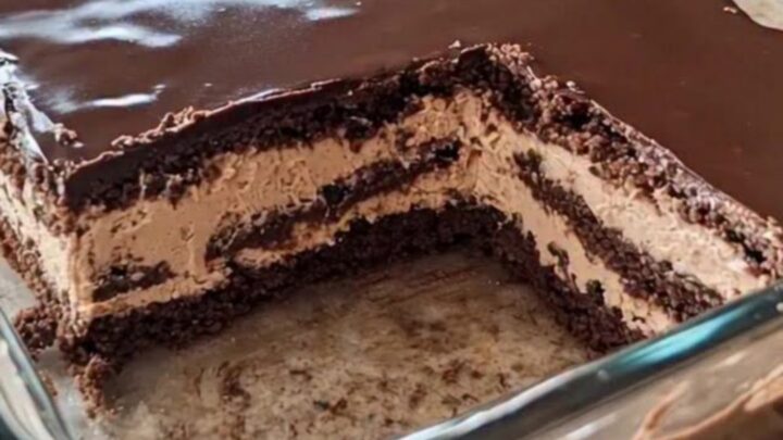 A close-up view of a chocolate icebox cake in a glass dish, showing distinct layers of mousse and cookies.