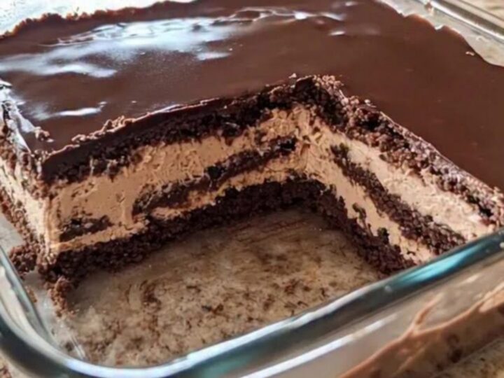 A close-up view of a chocolate icebox cake in a glass dish, showing distinct layers of mousse and cookies.