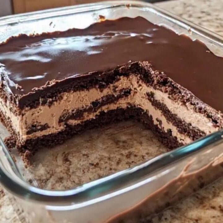 A close-up view of a chocolate icebox cake in a glass dish, showing distinct layers of mousse and cookies.