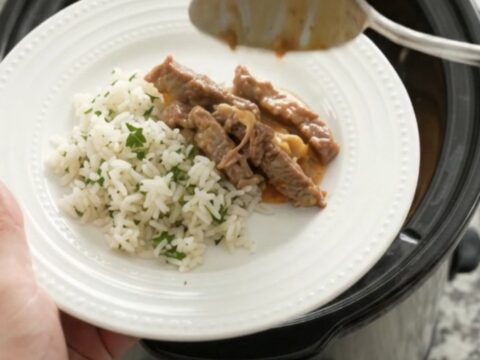 Crockpot cheddar taco steak with creamy sauce and pinto beans, served over rice