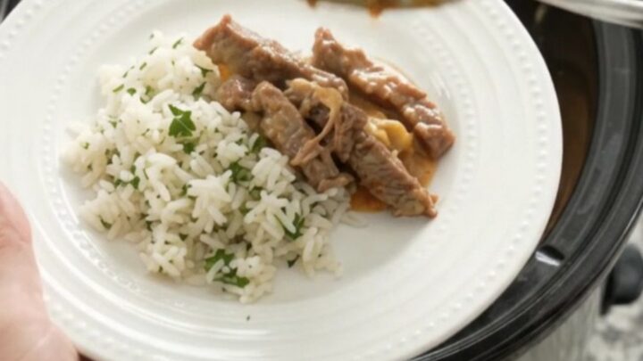 Crockpot cheddar taco steak with creamy sauce and pinto beans, served over rice