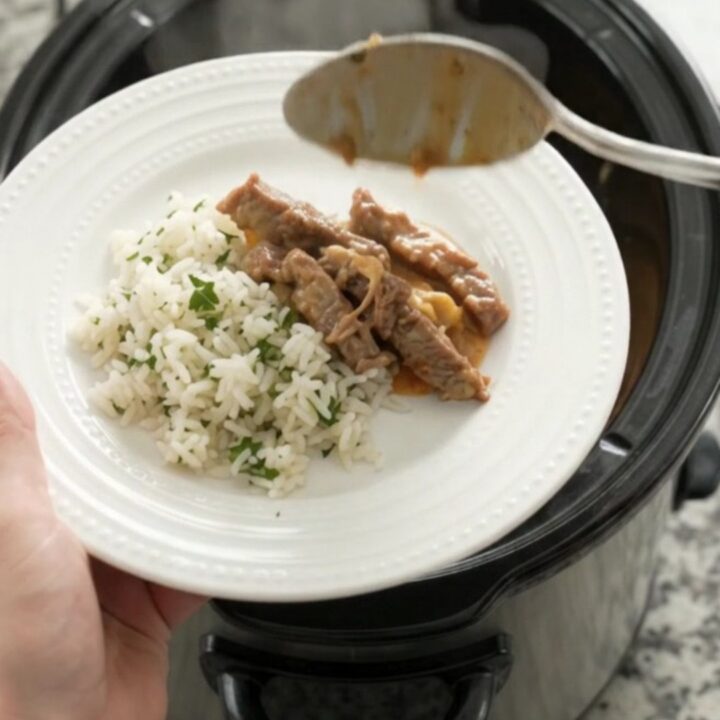 Crockpot cheddar taco steak with creamy sauce and pinto beans, served over rice