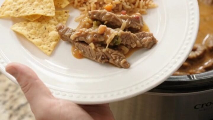 Slow cooker filled with tender skirt steak strips in a creamy pepper jack queso sauce