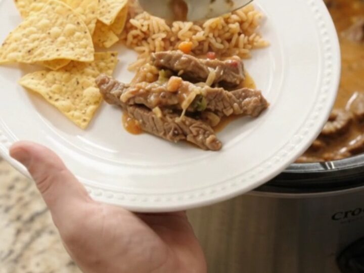 Slow cooker filled with tender skirt steak strips in a creamy pepper jack queso sauce