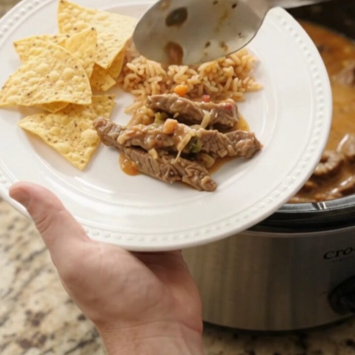 Slow cooker filled with tender skirt steak strips in a creamy pepper jack queso sauce