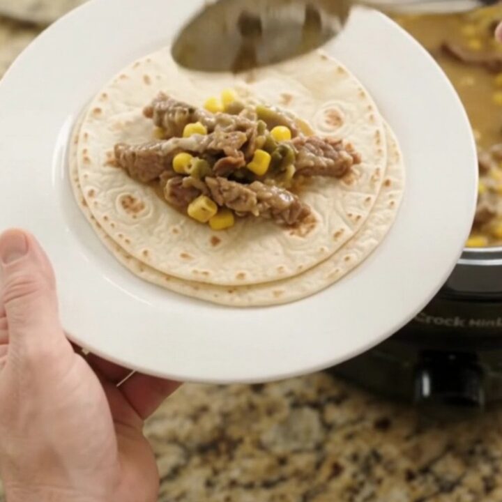 Slow cooker filled with creamy Monterey Jack sauce, tender skirt steak strips, corn, and green chiles.