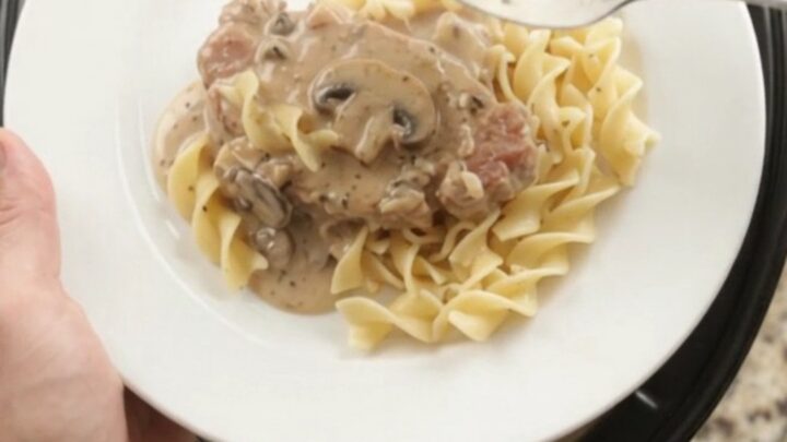 Crockpot sour cream ranch mushroom pork chops in a slow cooker, creamy gravy bubbling