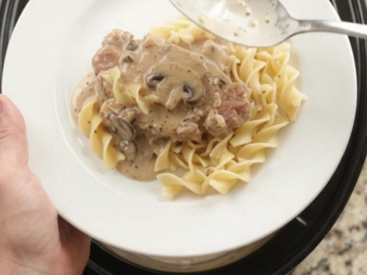 Crockpot sour cream ranch mushroom pork chops in a slow cooker, creamy gravy bubbling
