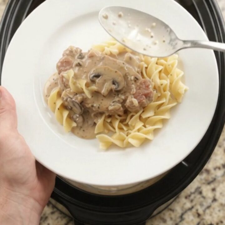 Crockpot sour cream ranch mushroom pork chops in a slow cooker, creamy gravy bubbling