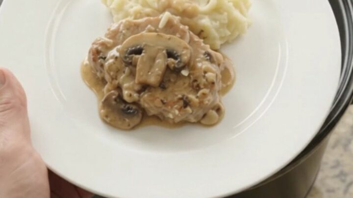 Slow cooker full of creamy Gruyère ranch mushroom pork chops with bubbling sauce