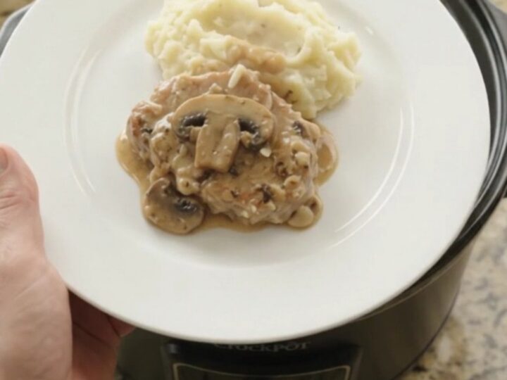 Slow cooker full of creamy Gruyère ranch mushroom pork chops with bubbling sauce