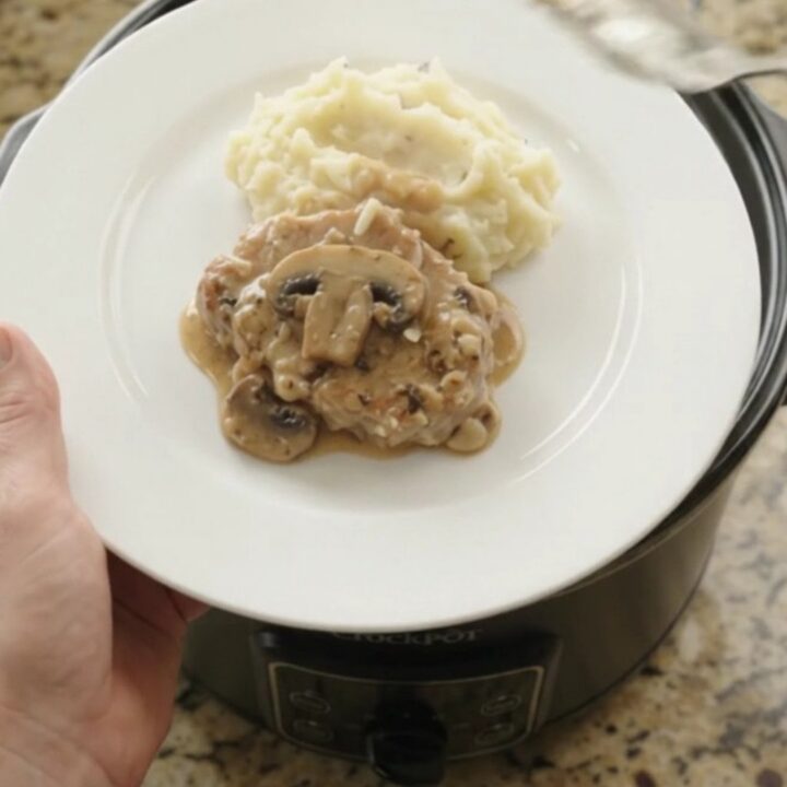 Slow cooker full of creamy Gruyère ranch mushroom pork chops with bubbling sauce