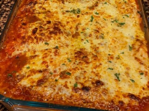 A thick, steaming slice of million dollar lasagna showing visible layers of meat sauce, ricotta, and melted cheese.