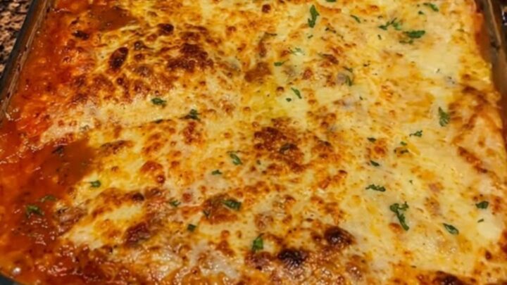 A thick, steaming slice of million dollar lasagna showing visible layers of meat sauce, ricotta, and melted cheese.