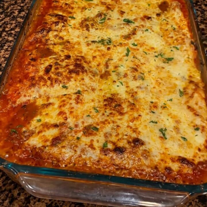 A thick, steaming slice of million dollar lasagna showing visible layers of meat sauce, ricotta, and melted cheese.