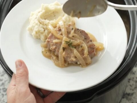 Slow cooker pork chops in a creamy onion sauce with thyme, served in the crockpot