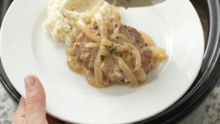 Slow cooker pork chops in a creamy onion sauce with thyme, served in the crockpot