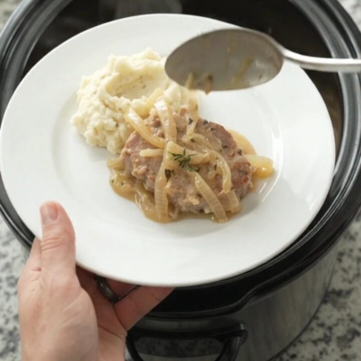 Slow cooker pork chops in a creamy onion sauce with thyme, served in the crockpot