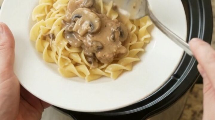 Slow cooker ribeye pork chops in creamy mushroom ranch sauce, topped with a spoonful of gravy.