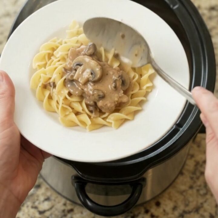 Slow cooker ribeye pork chops in creamy mushroom ranch sauce, topped with a spoonful of gravy.