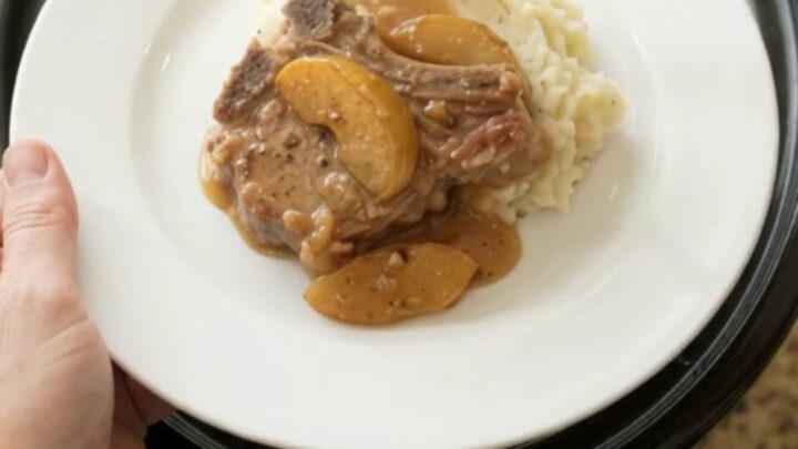 Slow cooker pork chops with apples and cream sauce in a black crockpot