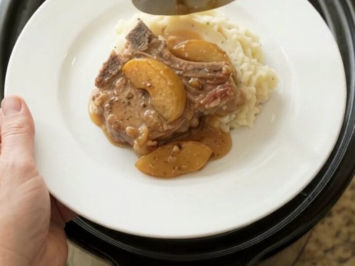 Slow cooker pork chops with apples and cream sauce in a black crockpot