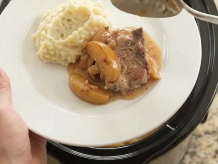 Slow cooker full of bubbling Gruyère apple cider pork chops with apples and cream sauce