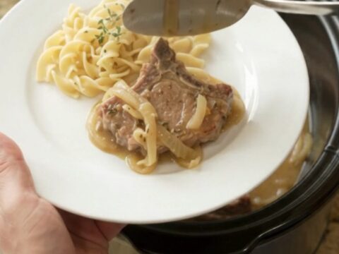 Slow cooker pork chops with creamy onion sauce in a black crockpot
