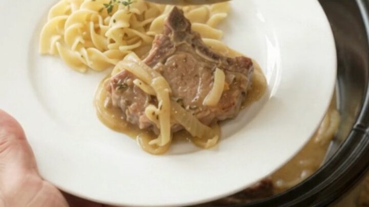 Slow cooker pork chops with creamy onion sauce in a black crockpot