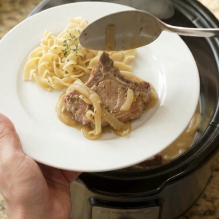Slow cooker pork chops with creamy onion sauce in a black crockpot