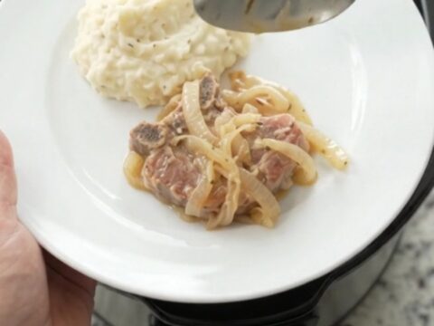 Slow-cooked ribeye pork chops in a creamy French onion sauce in a black Crockpot