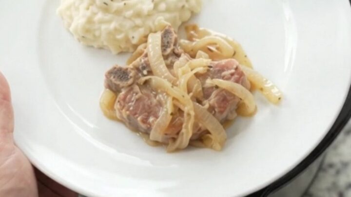 Slow-cooked ribeye pork chops in a creamy French onion sauce in a black Crockpot