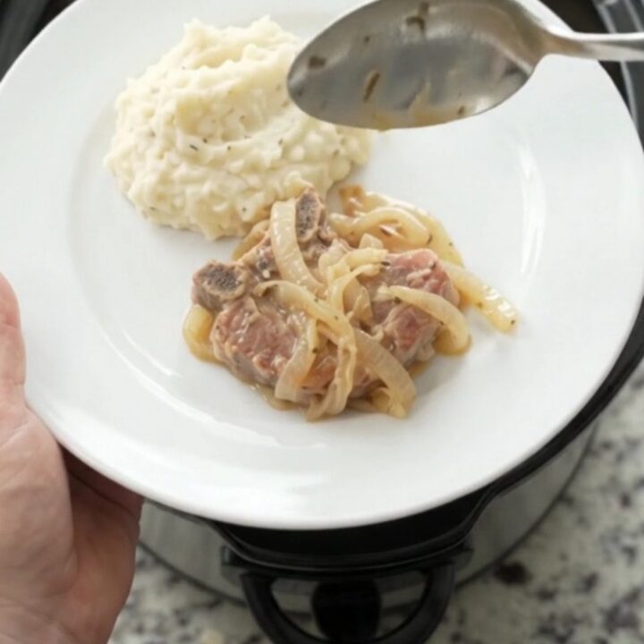 Slow-cooked ribeye pork chops in a creamy French onion sauce in a black Crockpot