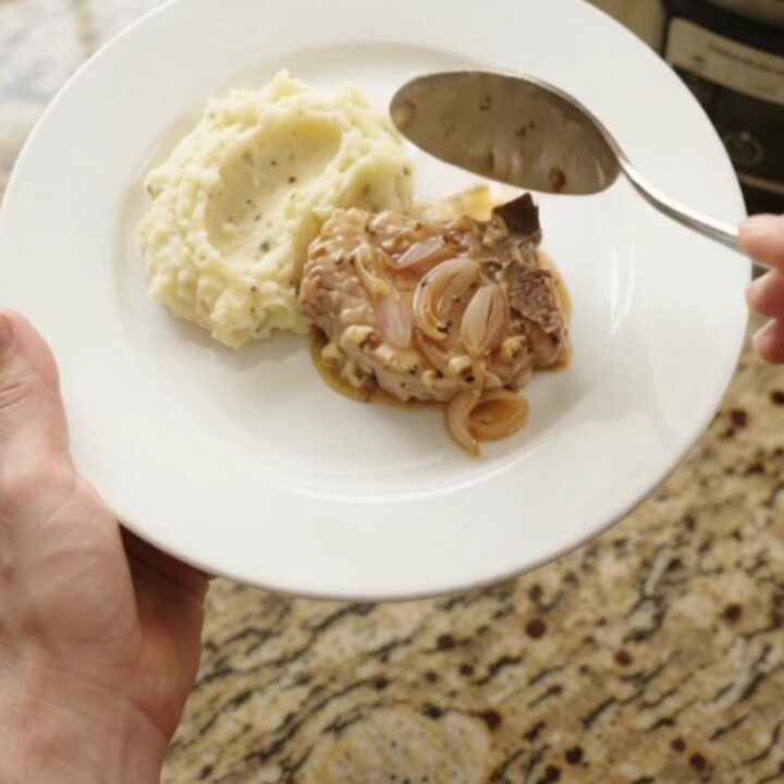 Bone-in pork chops in a bubbling Gruyère cream sauce with honey-Dijon shallots in a slow cooker.