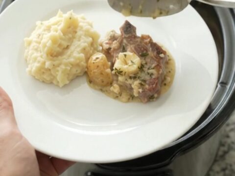 Bone-in ribeye pork chops and baby potatoes in a creamy Gruyère sauce in a slow cooker.