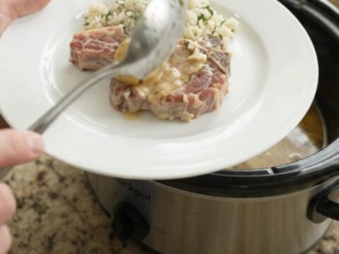 Crockpot full of pork chops and potatoes in creamy Parmesan sauce