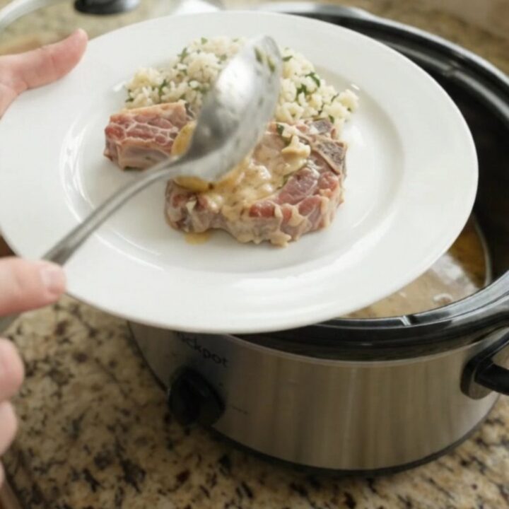 Crockpot full of pork chops and potatoes in creamy Parmesan sauce